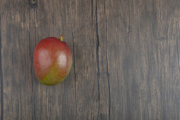 Photo of single fresh mango placed on wooden surface