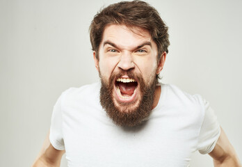 Portrait of an emotional man in a white T-shirt and a thick beard