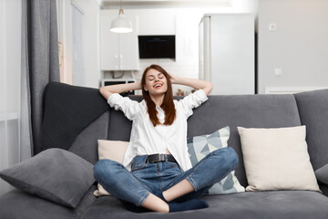 Obraz premium woman with closed eyes sitting on the couch threw back her head at home