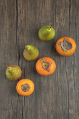 Delicious fuyu persimmons and ripe pears on wooden surface