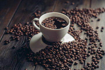coffee beans on a wooden background and a cup on a saucer close-up macro photography