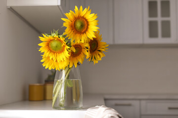Vase with beautiful yellow sunflowers in kitchen, space for text