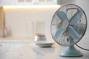 Fototapeta Modern electric fan on countertop in kitchen, space for text. Summer heat obraz