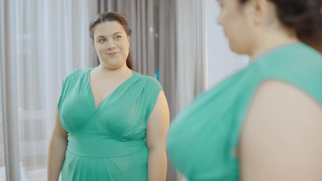 Beautiful plus size woman looking at mirror, preparing for date, self-confidence