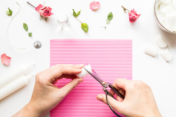 DIY concept. Female hands cut wax with scissors. Ingredients for making handmade candles on a light background. Flat lay. View from above.