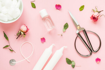 DIY concept. Wax, wick, dry roses - ingredients for making handmade candles on a pink background. Flat lay. View from above.