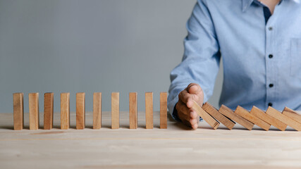 Businessman hand stopping the domino wooden effect concept for Planning,risk and strategy in business.