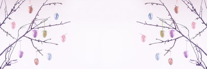 easter background with decorations in the form of easter eggs on tree branches on light backdrop with copy space