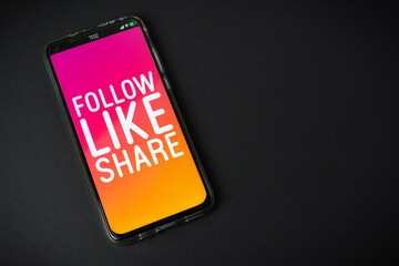 Follow Like Share - Phone on black background
