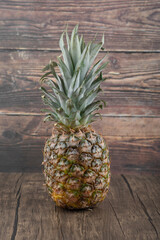 Photo of ripe juicy pineapple placed on wooden background