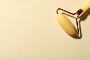 Natural jade face roller on beige background, top view. Space for text