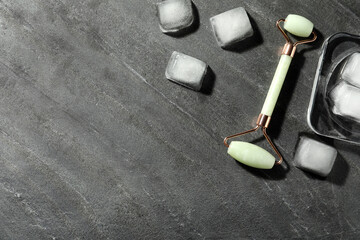 Natural jade face roller and ice cubes on grey background, flat lay. Space for text © New Africa