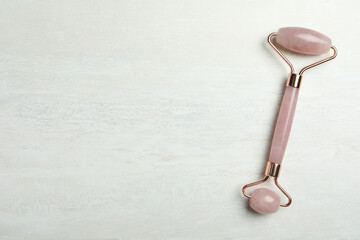 Natural jade face roller on light background, top view. Space for text