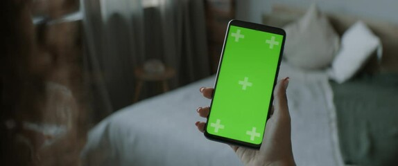 GREEN SCREEN CHROMA KEY Unrecognizable Black African American female using her phone inside her apartment. Vertical orientation. Scrolling and touch clicking center of the screen