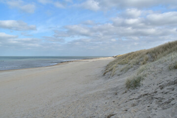 An open expanse of North Sea coastline and sand dunes at Domburg in the Netherlands under a blue cloudy sky.