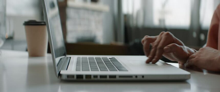 CU on hands of Caucasian female working from home, using her laptop. Typing and scrolling. Remote work during COVID-19 pandemic