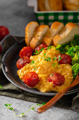 Scrambled eggs with salad and grilled tomatoes