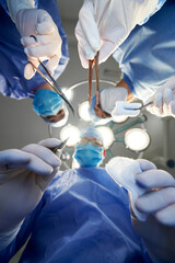 View from below, focus on doctors hands holding scalpel, scissors and forceps with tampon while...