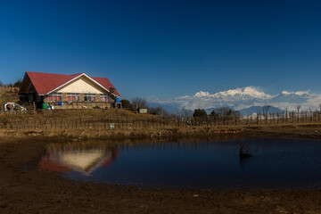 Obraz premium mountA small hut in front of small pond and Kanchenjunga in background.