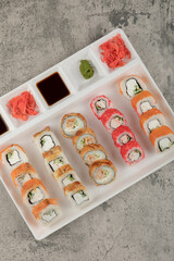 A white board with different types of delicious sushi rolls on stone table