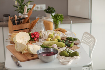 Cucumbers, courgettes and red radishes in the kitchen with a white table.
