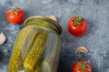 Close up photo of fresh tomatoes and garlic with pickle jar on grey background