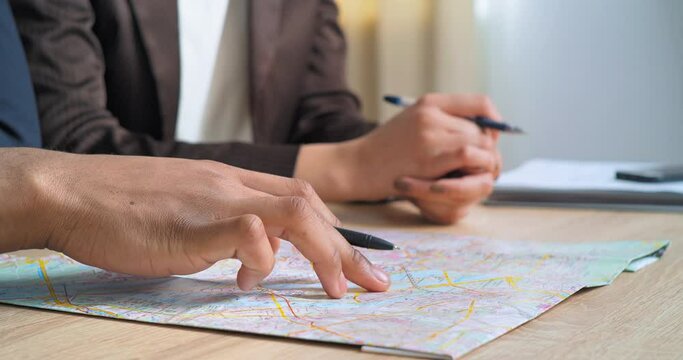 Close-up male and female hands holding pens and world map in office two partners businesspersons engineers women and men looking at plan choose city for implementation of project to build new company