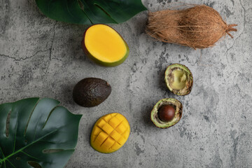 Sliced tropical fruit mango, coconut and broken avocado on marble surface