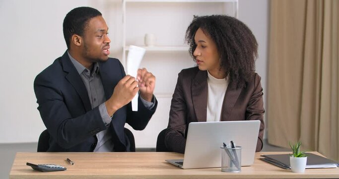 Partners coworkers afro american businessman and businesswoman quarreling argue over document data boss showing paper with mistake angry screams scolding female secretary, misunderstanding concept