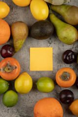 Bunch of delicious fresh fruits and empty memo pad on marble surface