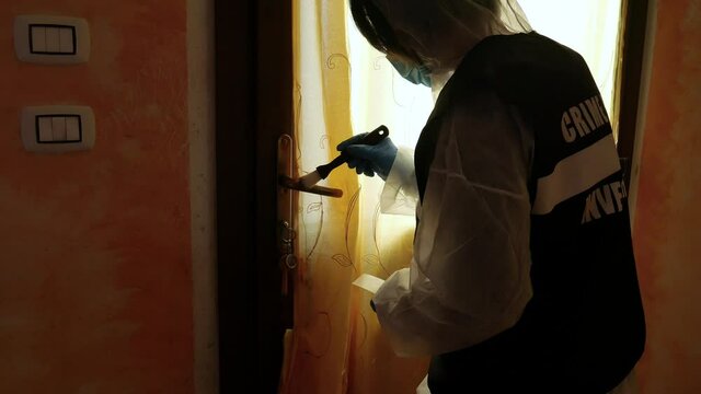 csi investigator at the crime scene who inspects with blue flashlights and takes scientific evidence to take to the laboratory taken from the handle of a house door where a murder was committed