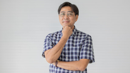 Portrait close up shot of middle aged asian male model with short black hair wearing blue plaid shirt with stand smiling fold his arms in smart pose on white background