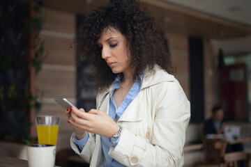 Young girl is sitting in a cafe and communicating with a mobile phone