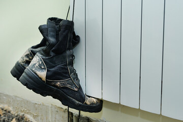 Old dirty ragged builders boots hangs on lace at construction site