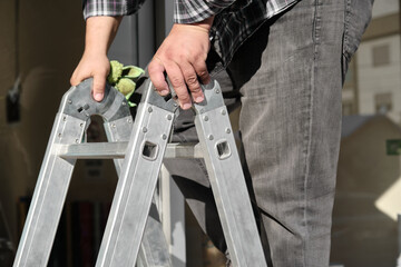Folding ladder with a person on it. Folding ladder details. Aluminum folding ladder.  © ozencdeniz