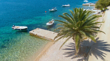 AERIAL: Flying above a pebble shore in Dalmatia with boats moored to the jetty