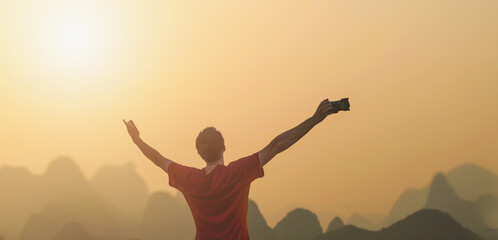 man hand-raising on top of mountain and sunset sky.
