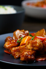 Sweet and sour chicken, fried rice with egg and glass noodles salad served in ceramic bowls. Dark wooden table, high resolution
