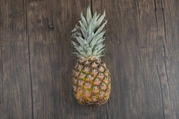 Photo of ripe juicy pineapple placed on wooden background