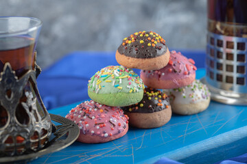 Close up photo of Glass of tea with jar of cookie on blue board
