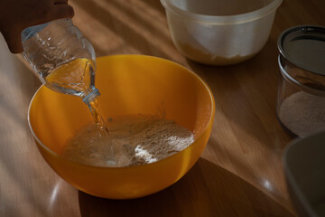 Close up of feminine hands mixing flour and water to make dough