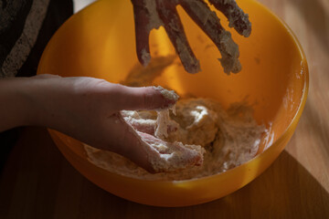 Close up of feminine hands mixing flour and water to make dough