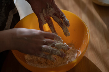 Close up of feminine hands mixing flour and water to make dough