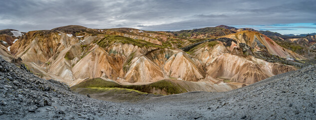 Beautiful panoramic Icelandic landscape of colorful rainbow volcanic Landmannalaugar mountains, at famous Laugavegur hiking trail with dramatic snowy sky, and red volcano soil in Iceland.