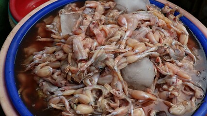 Raw frog meat, cutting frog meat for food, lay on ice at traditional market