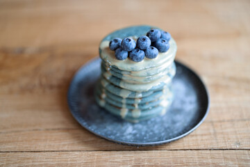 Fototapeta na wymiar Blue american pancakes decorated with blueberry and caramel souse on vintage plate on wood table. Homemade tasty food. Celebration of Shrovetide.