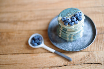 Blue american pancakes decorated with blueberry and caramel souse on vintage plate on wood table. Homemade tasty food. Celebration of Shrovetide.