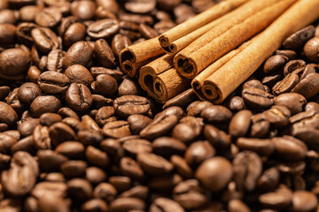 Obraz na płótnie Canvas Cinnamon sticks on a background of freshly roasted coffee beans. Coffee beans texture