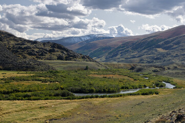 Naklejka premium Dramatic desert steppe river valley on a highland mountain plateau with ranges of hills on a horizon storm skyline