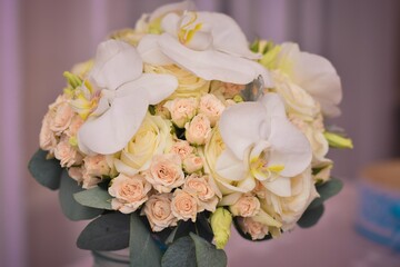 A bouquet of flowers. Roses are light pink and white orchids. Flowers in a jar.